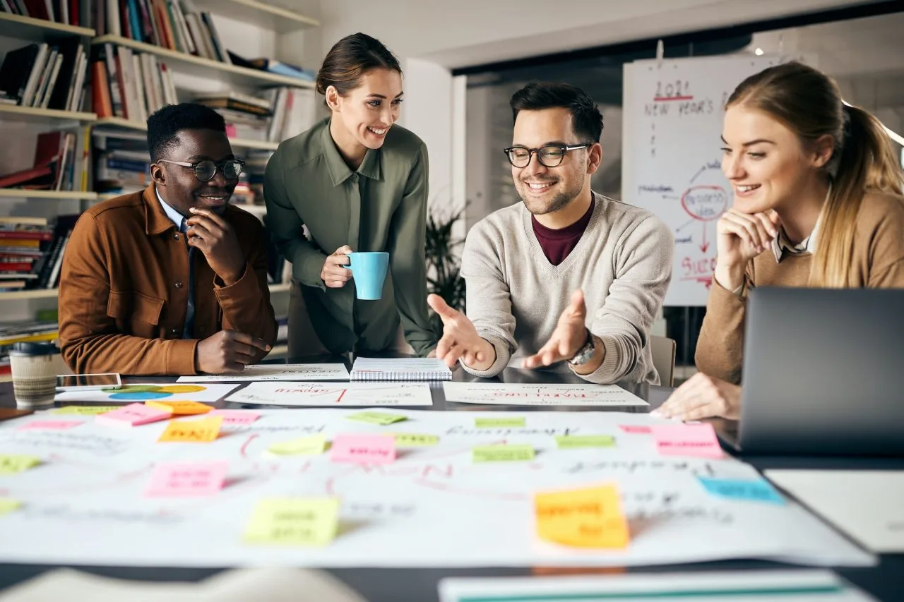 Equipo de marketing reunido alrededor de una mesa con notas adhesivas y un portátil